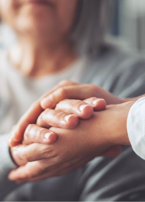 Photo close-up of younger hands holding the hand of an older adult.