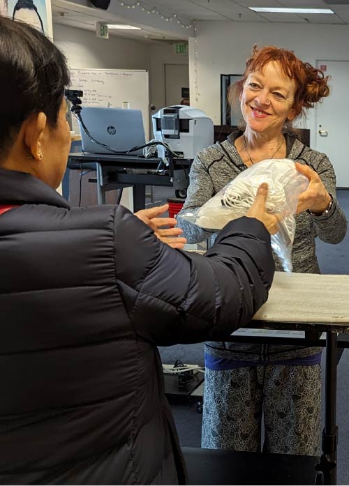 Photo of a staff member at the San Francisco IHSS Public Authority distributing a PPE kit to a Provider.